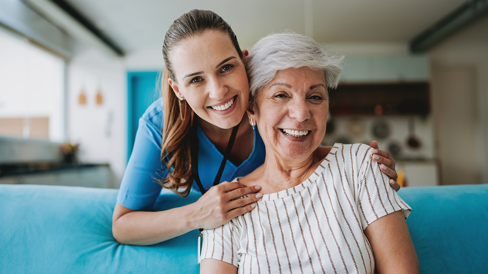 Two women, a doctor and a patient, sitting together smiling in a clinical setting.